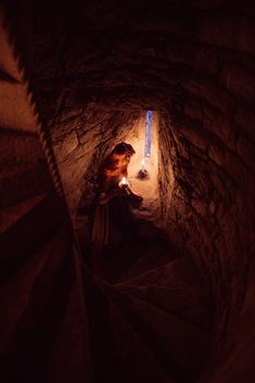 a woman sitting on top of a set of stairs next to a light in a tunnel