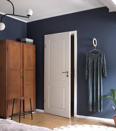 a bedroom with blue walls and wooden furniture in front of the door to another room