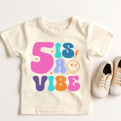 a t - shirt and pair of shoes sitting next to each other