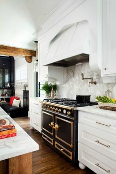 a kitchen with white cabinets and gold trimmings on the stove top, along with marble counter tops