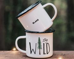 two white coffee mugs sitting on top of each other with the words wild printed on them