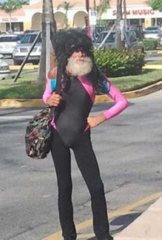 a man in a wet suit is standing on the side of the road with a bag