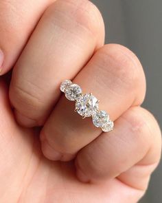 a woman's hand holding a three stone diamond ring