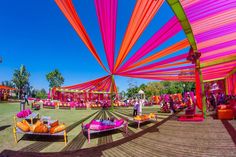 an outdoor event with bright colored draping on the walls and tables under it