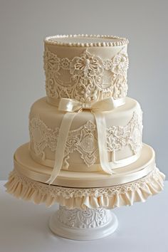 a three tiered wedding cake with lace and bows