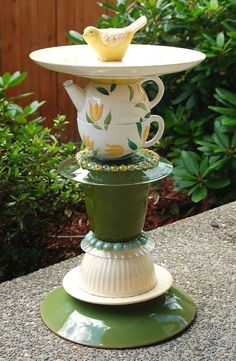 a stack of tea cups sitting on top of each other in front of some bushes