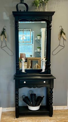 a black dresser with a mirror and vases on the top shelf in front of it