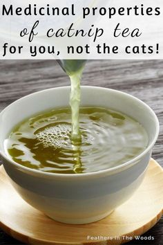 a white bowl filled with green liquid on top of a wooden plate