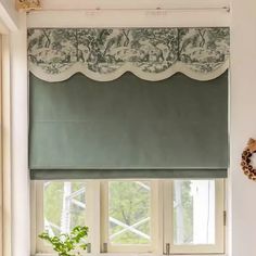 a kitchen window with green roman blinds and white counter tops, along with a potted plant