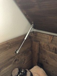 a teddy bear sitting on top of a bed under a slanted ceiling with wooden paneling