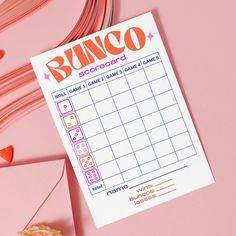 a bunco score card sitting on top of a pink table next to some candy