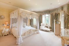 a fancy bedroom with four poster bed and chandelier on the ceiling, along with white furniture