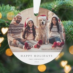 a christmas ornament with two people and a dog in front of a tree