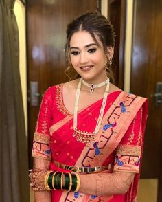 a woman in a red sari and jewelry posing for the camera with her hands on her hips