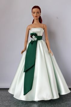 the doll is wearing a white and green dress with a flower on it's waist