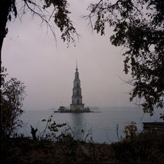 an island in the middle of water with a clock tower on it's side