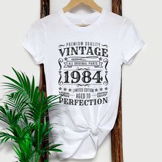 If you're looking for a unique and stylish way to wear on your 40th Birthday, then check out our vintage 1984 shirt! This shirt features a soft, comfortable fabric and a cool, retro design. Whether you're dressing up for a special occasion or just want to feel nostalgic, this shirt is perfect for you. Our vintage 1984 shirt is also great for birthdays, anniversaries, or any other special day. So don't wait any longer - order your vintage 1984 shirt today! 1980S, Vintage 1984 Shirt, Vintage Shirt, Vintage T Shirt 80S, 1984 birthday TShirt, Retro Birthday Tee, 1984 Birthday Shirt, 40th Birthday Gift, 40Th Birthday Shirt, Vintage Birthday Tee, 1984 Gift Tee, Classic Shirt, Vintage T Shirt #Vintage1984 #1984Birthday #RetroStyle #VintageTShirt #40thBirthday #1984Shirt #ClassicDesign #BirthdayTe Vintage 1980 Tshirt Birthday, Classic Graphic Print T-shirt For Birthday, Vintage White T-shirt For Birthday, Retro White Tops For Anniversary, Summer Anniversary T-shirt With Letter Print, Anniversary Letter Print T-shirt For Summer, Vintage Cotton Tops For Anniversary, Summer Cotton Tops For Anniversary, Cotton Tops For Summer Anniversary