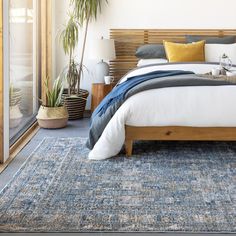 a bedroom with a bed, rug and plants