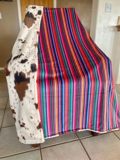 a cow print blanket sitting on top of a wooden chair