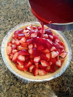 strawberries in a pie pan being drizzled with syrup