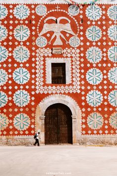 a person walking in front of a red and white building with blue flowers on it