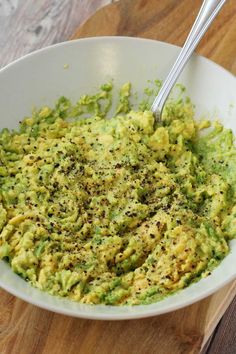 a white bowl filled with guacamole on top of a wooden cutting board