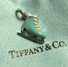 there is a pendant with a roller skate on it that says tiffany & co in gold lettering