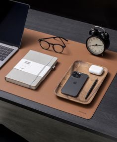 an apple laptop computer sitting on top of a desk next to a phone and other items