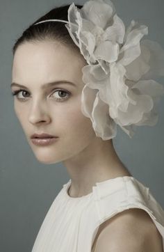 a woman with a flower in her hair wearing a white dress and headpieces