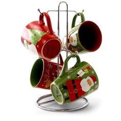 four coffee mugs on a stand with santa's hats and stockings hanging from them