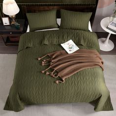 a bed with green bedspread and pillows