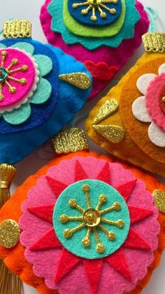 four different colored felt flowers with tassels and gold sequins on them