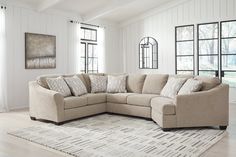 a living room with a large sectional couch and rug in front of the window on the floor