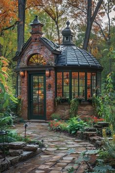 a small brick building surrounded by trees and flowers