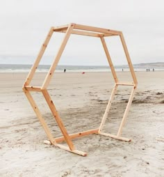 a wooden structure sitting on top of a sandy beach next to the ocean with people in the background