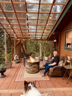 a man sitting on a chair next to a fire pit in the middle of a wooden deck