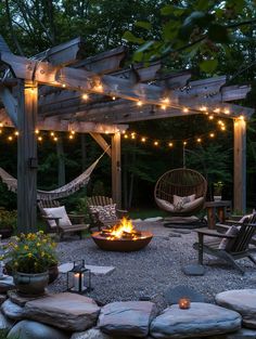 an outdoor fire pit surrounded by chairs and lights