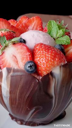 a chocolate dessert with strawberries and blueberries in it on a white plate, ready to be eaten