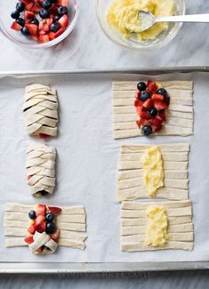 some fruit and pastry items on a baking sheet with bowls of yogurt, strawberries, and blueberries