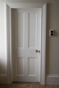 an open white door in a room with wooden floors