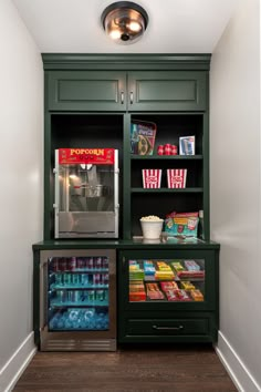 a green bookcase filled with lots of books next to a wall mounted popcorn dispenser