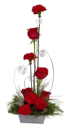 red carnations and greenery in a white vase with silver circles around the stems