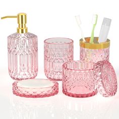 pink glass bathroom accessories including toothbrushes and soap dispenser