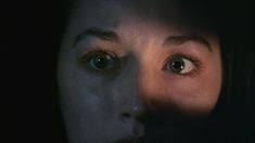 a woman's face is shown in the dark, with her eyes wide open