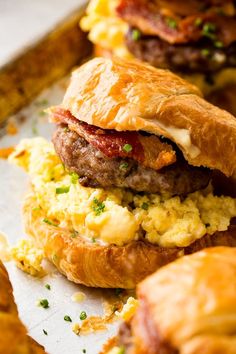 breakfast sandwich with bacon and eggs on croissants next to other pastries