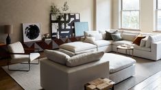 a living room filled with white furniture and large windows in the wall behind it,