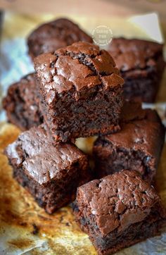 chocolate brownies stacked on top of each other in front of a piece of parchment paper