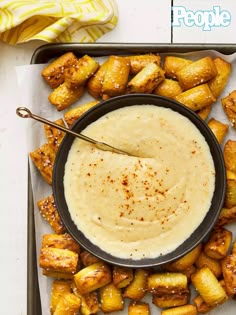 a bowl of dip surrounded by fried pineapples on a tray with a spoon