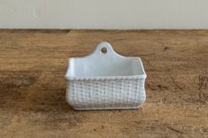 a small white basket sitting on top of a wooden table