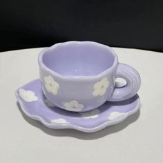 a purple cup and saucer sitting on top of a white table with polka dots